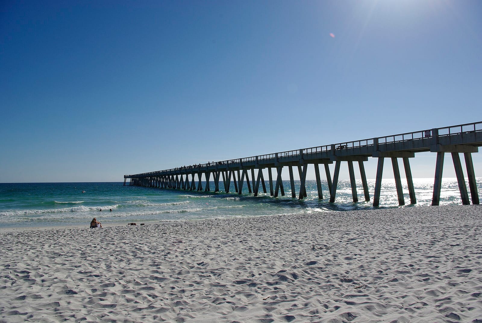 Navarre Beach Fishing Pier extending into the Gulf over white sand and clear green water, seen from the beach