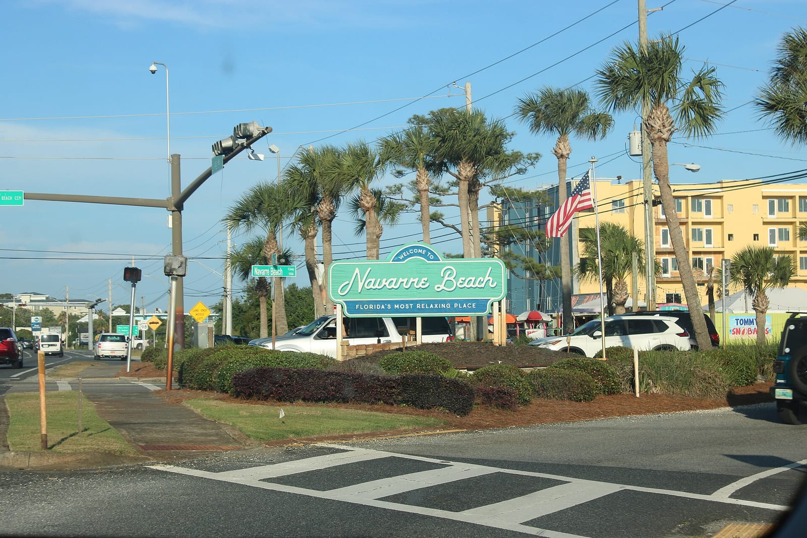 Welcome to Navarre Beach sign beside palm trees at the Navarre Beach Causeway intersection on US-98 in Florida