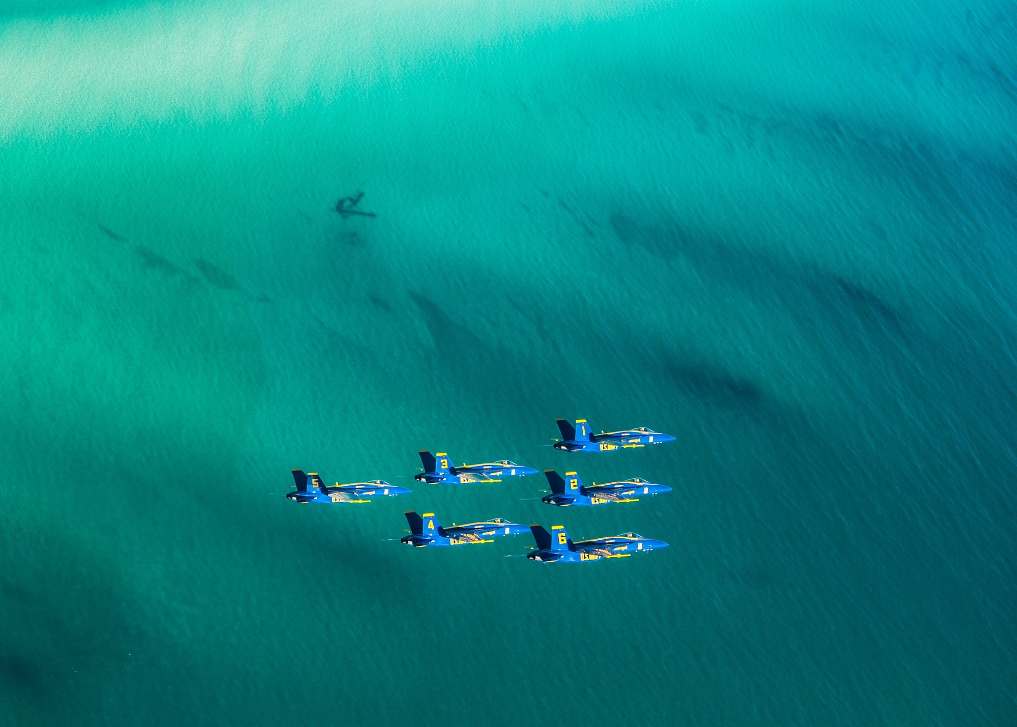 Blue Angels Super Hornets in formation above coastal water near NAS Pensacola