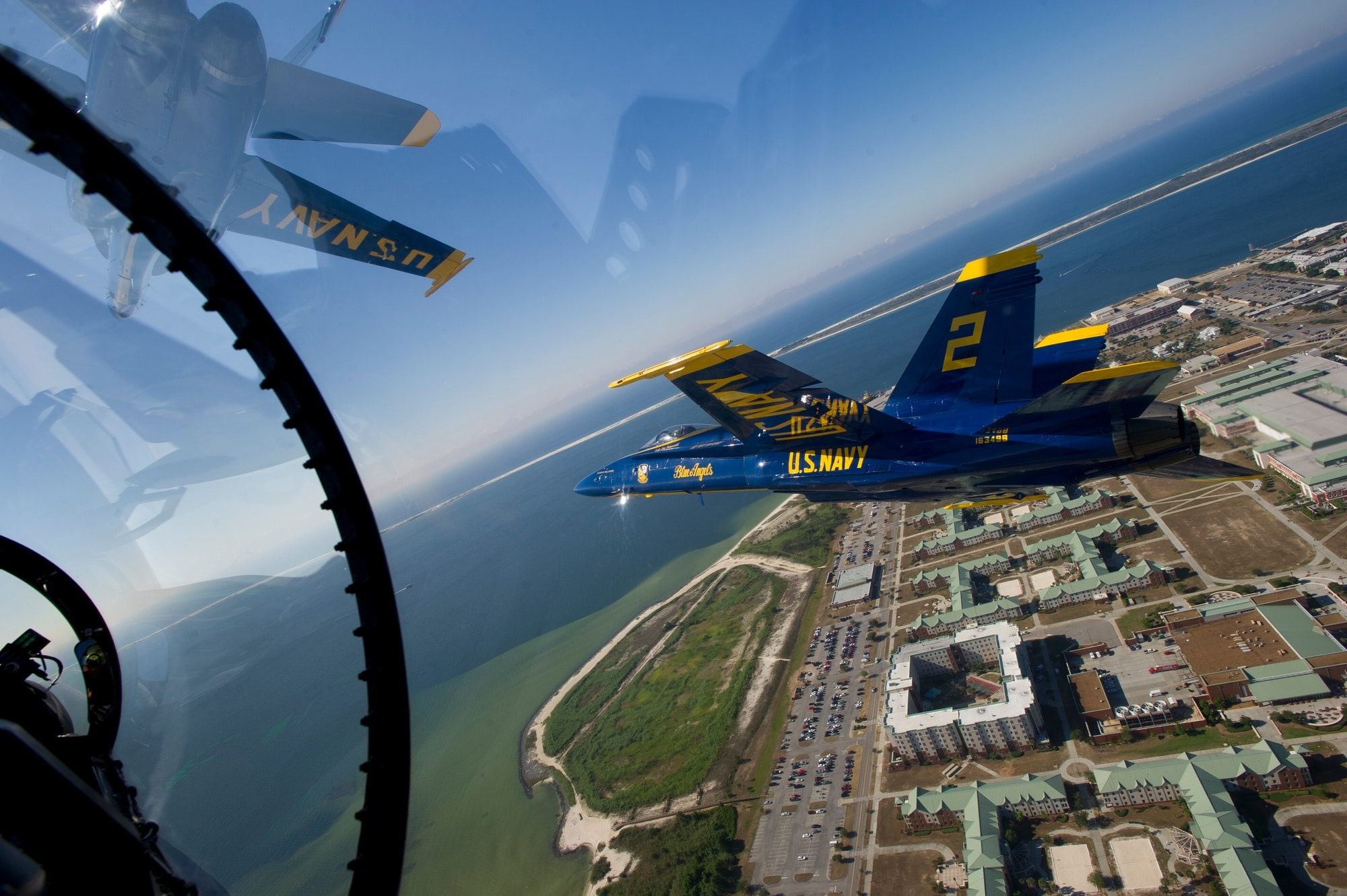 A Blue Angels Hornet flying beside another aircraft above Naval Air Station Pensacola