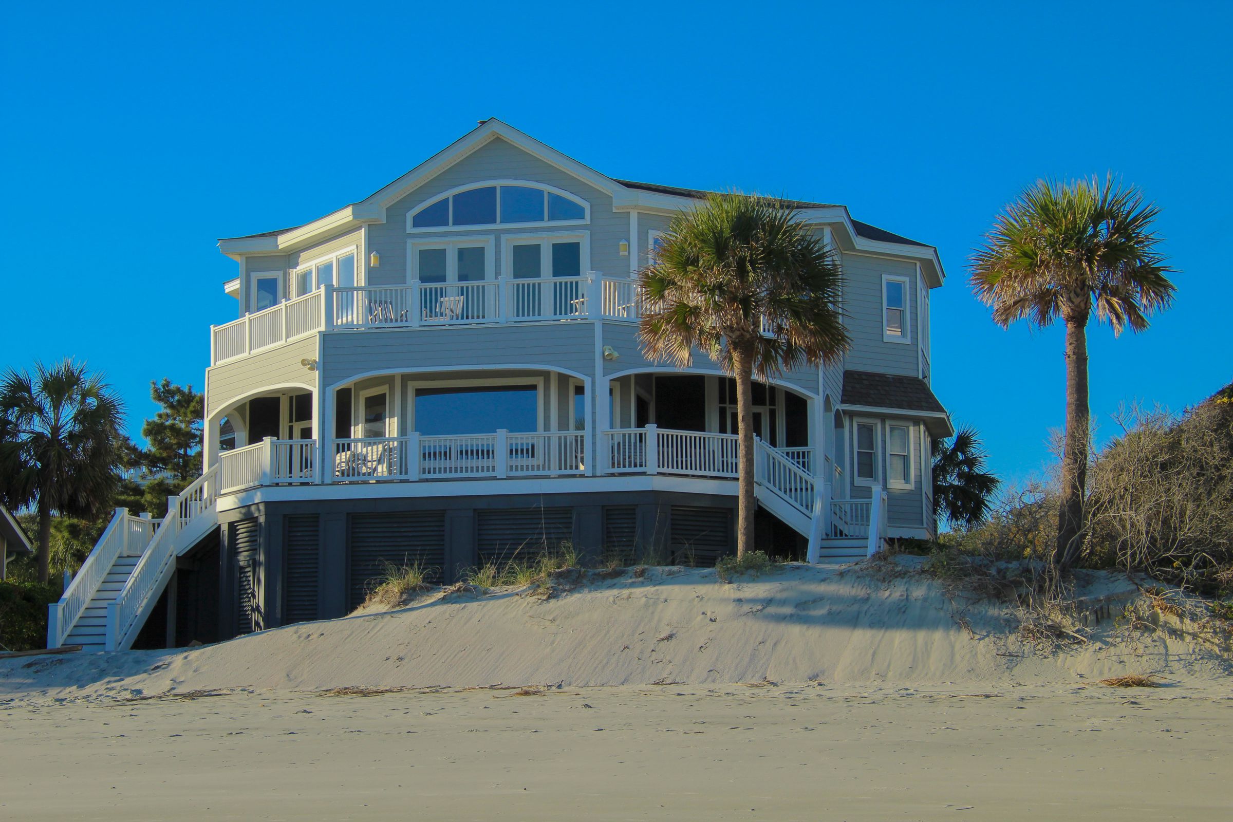 A raised beach house with wraparound porches on a sand dune