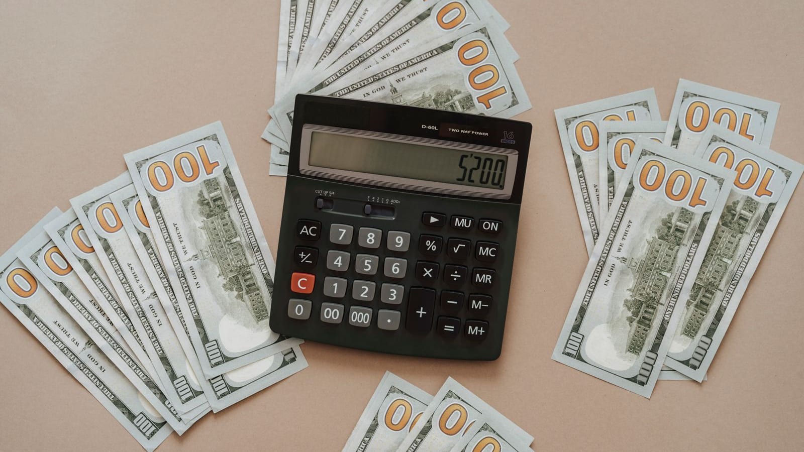 Calculator and hundred dollar bills representing a BAH housing budget