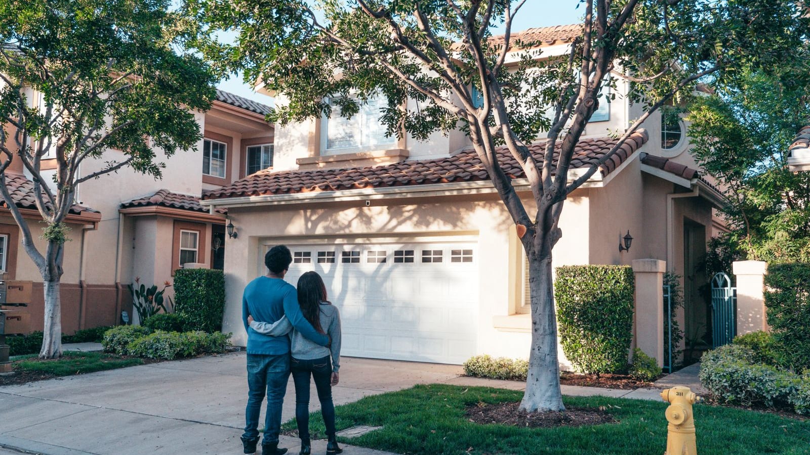 A happy young couple embracing outside the front of their new suburban home